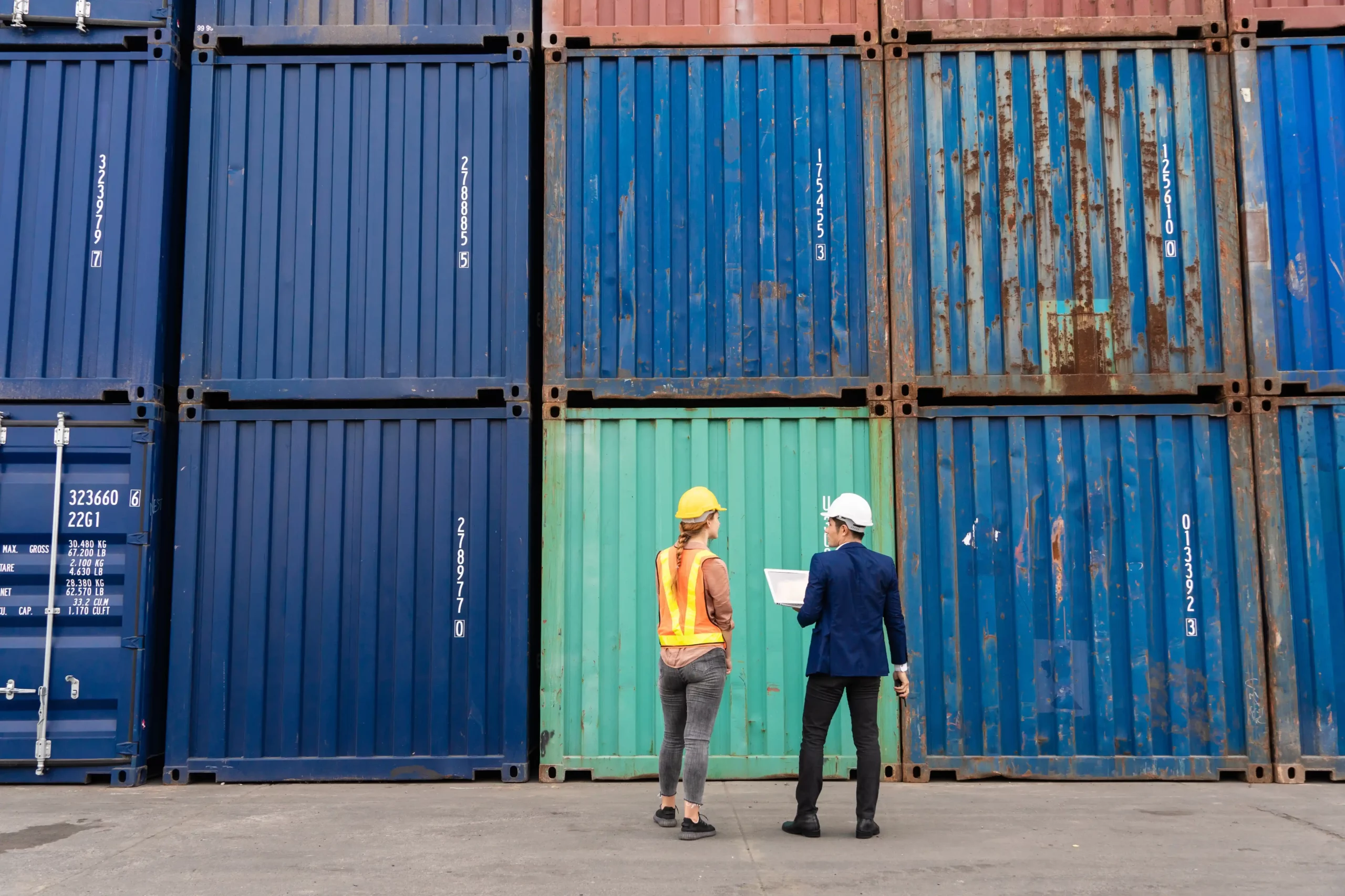 Port workers inspecting shipping containers with tablets for electronic documentation